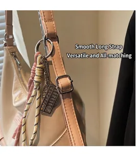 Détail du sac crème avec bandoulière rose, boucle argentée et pendentif boulier
