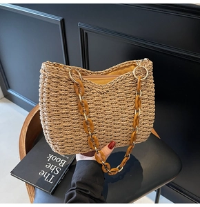 Close-up of woven straw handbag with brown acrylic chunky chain strap and metal rings