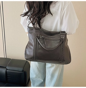 Detail of vintage brown soft leather tote bag featuring braided straps and zip pocket