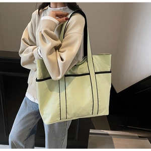 Close-up of a light green large-capacity tote bag with black contrast trim detailing