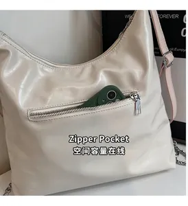 Détail d'un sac à bandoulière en cuir blanc crème doté d'une poche zippée fonctionnelle