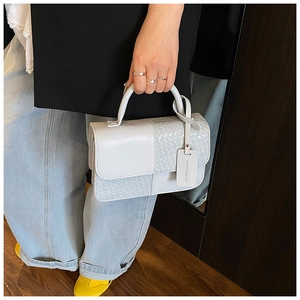 Détail du petit sac carré bleu clair avec panneau en cuir tressé et étiquette mode