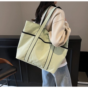 Detail of large mint green tote bag with black strap and spacious front pocket