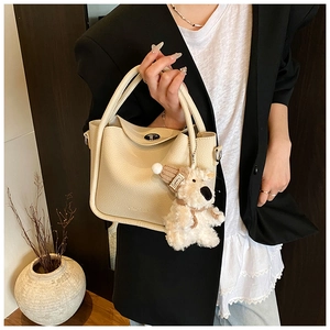 Détail du sac à main en cuir crème avec fermoir rotatif argenté et charmant pendentif chien