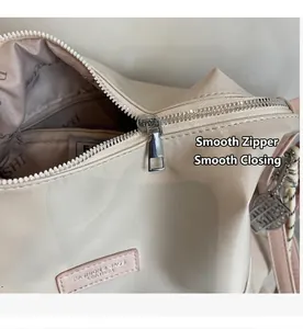 Détail du zip métallique argenté et de l'étiquette rose du sac cabas blanc crème