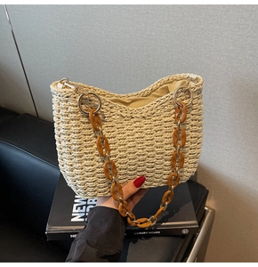 Close-up of handmade straw shoulder bag with amber acrylic chain and woven texture