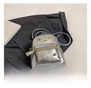 Detail shot of silver mini backpack with gold dog paw and bone studs on the front pocket