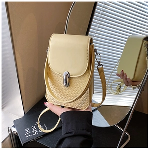 Close-up of small yellow crossbody bag featuring woven texture and silver metal clasp
