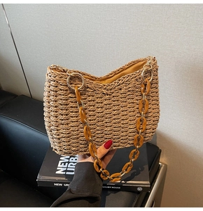Macro shot of straw woven tote bag featuring amber acrylic chain and metal rings