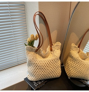 Dettaglio della trama traforata all'uncinetto e manici in pelle marrone della borsa beige