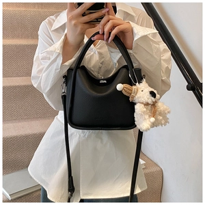 Détail d'un mini sac en cuir noir grainé avec un charmant pendentif chien en peluche