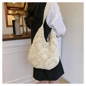 Détail macro de la couture florale au crochet blanc cassé sur un sac hobo vintage