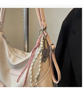 Détail du sac cabas blanc crème avec bandoulière en cuir rose et pendentif boulier argenté