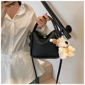 Détail du sac seau en cuir noir avec un joli pendentif de chiot en peluche doux