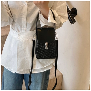 Detail of a black crossbody phone bag featuring crocodile texture and silver metal lock