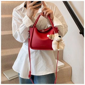 Détail du petit sac carré en cuir rouge texturé avec un joli charme d'ours en peluche blanc