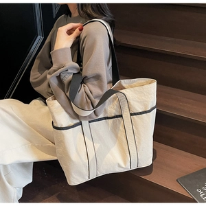 Close-up of cream large tote bag with contrast black straps on wooden stairs
