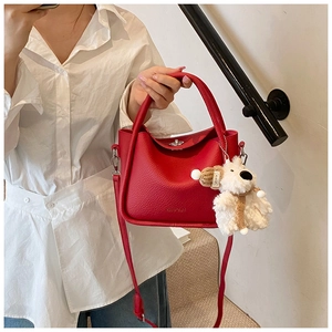 Détail du mini sac rouge en cuir grainé avec un porte-clés pelucheux en forme de chiot