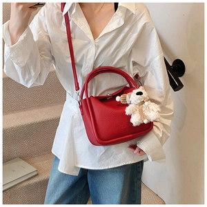 Mini sac rouge motif litchi avec pendentif ours blanc sur chemise blanche et jean bleu