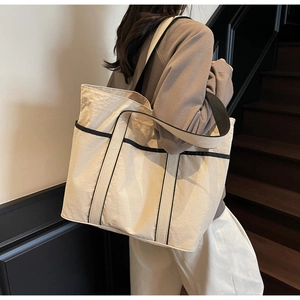 Detailed shot of large cream tote bag with contrast black trim and wide shoulder strap
