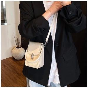 Detail of beige leather mini crossbody bag featuring a quilted pattern and silver twist lock