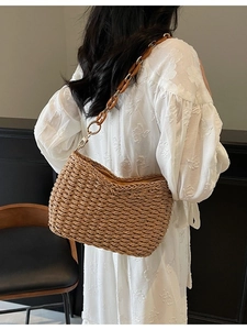 Handmade brown straw shoulder bag with amber resin chain strap on a model shoulder