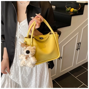 Détail du sac seau en cuir jaune avec motif litchi et charmant ours en peluche