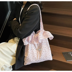 Detail of light purple floral tote bag featuring ruffled edges and magic pocket label