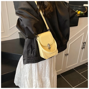 Detail of yellow crossbody bag featuring woven texture and silver metal lock closure