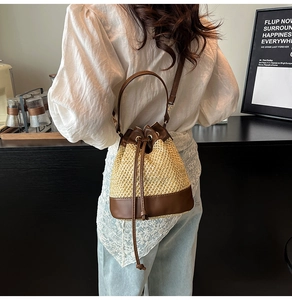 Detail view of woven straw bucket bag with dark brown leather straps on a model