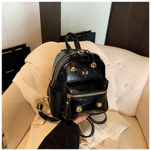 Detail of a mini black PU backpack featuring gold cat claw hardware and glossy finish