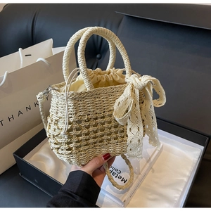 Détail d'un sac en paille tressée avec nœud en dentelle, chaîne dorée et doublure douce