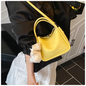 Détail d'un sac à main en cuir jaune vif avec un charmant petit ours en peluche blanc