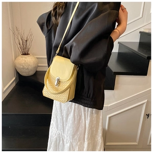 Detail of lemon yellow crossbody bag with woven texture and silver metal twist lock