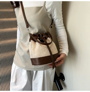 Detail of hand-woven straw bucket bag featuring a brown faux leather drawstring and golden hardware