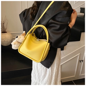 Gros plan du mini sac jaune vif en cuir grainé avec des détails métalliques argentés
