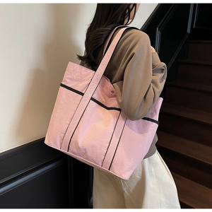 Side view of a large pink nylon tote bag with black contrast straps on a model