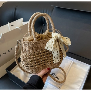 Détail d'un sac en paille bohème avec nœud en dentelle blanche et chaîne dorée