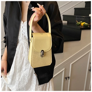 Detail showing the light yellow crocodile embossed texture and silver metal buckle of the bag