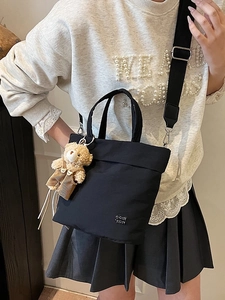 Minimalist black canvas tote bag with adjustable strap and cute teddy bear pendant