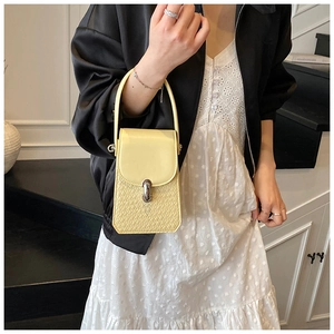 Detail view of the yellow leather crossbody bag with crocodile texture and metal twist lock
