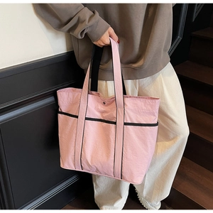 Detailed macro view of pink nylon tote bag with black contrast straps and spacious interior