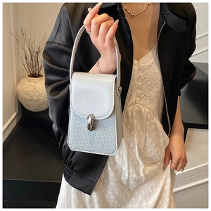 Detail of light blue crossbody bag featuring faux crocodile texture and silver twist lock
