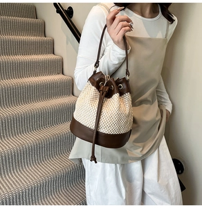 Detail of straw bucket bag with brown leather trim and drawstring closure on shoulder