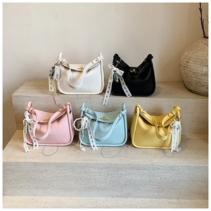 Close-up of five colorful textured leather handbags with lace ribbons and pearl charms