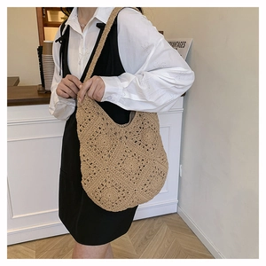 Détail d'un sac cabas en paille crochetée kaki avec texture tissée et bandoulière large