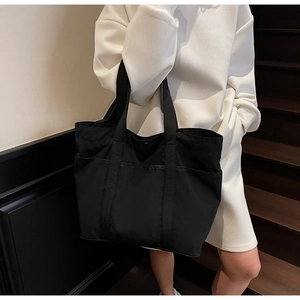 Detail of black tote bag featuring side pockets and a secure metal snap closure system