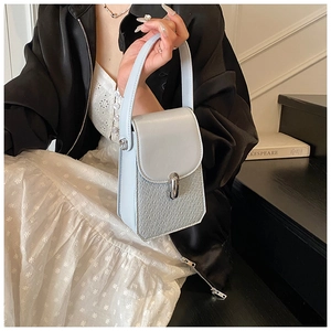 Detail of light blue faux crocodile leather handbag with silver metallic buckle on model