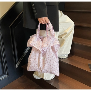 Detail view of pink floral ruffle tote bag with small red flower pattern and texture