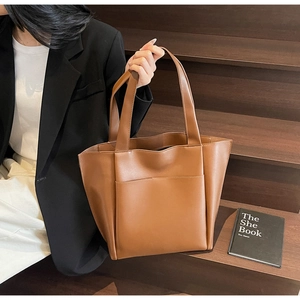 Detail of a caramel brown large tote bag with front pocket on wooden steps